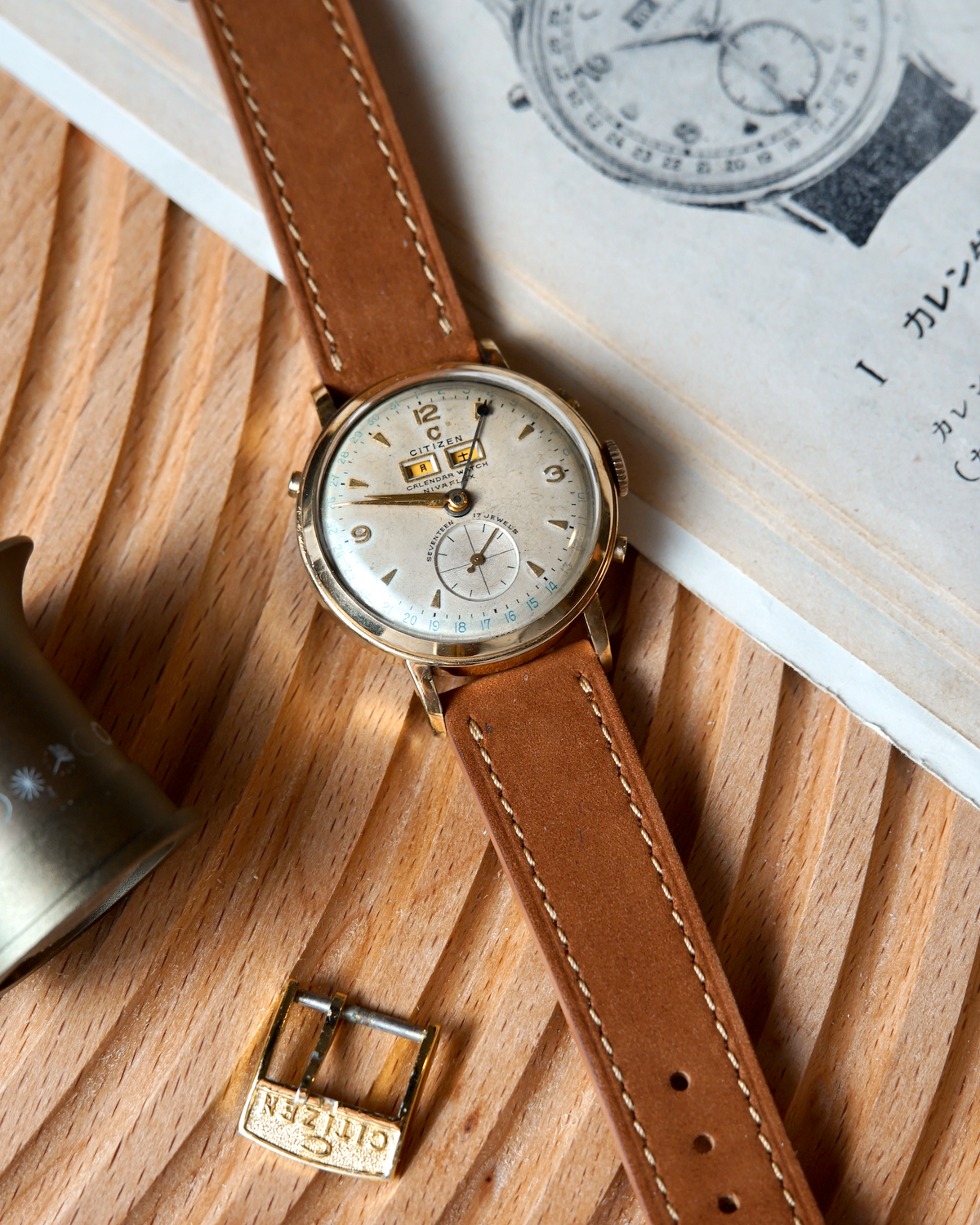 Vintage citizen watch with brown leather strap on a wooden surface