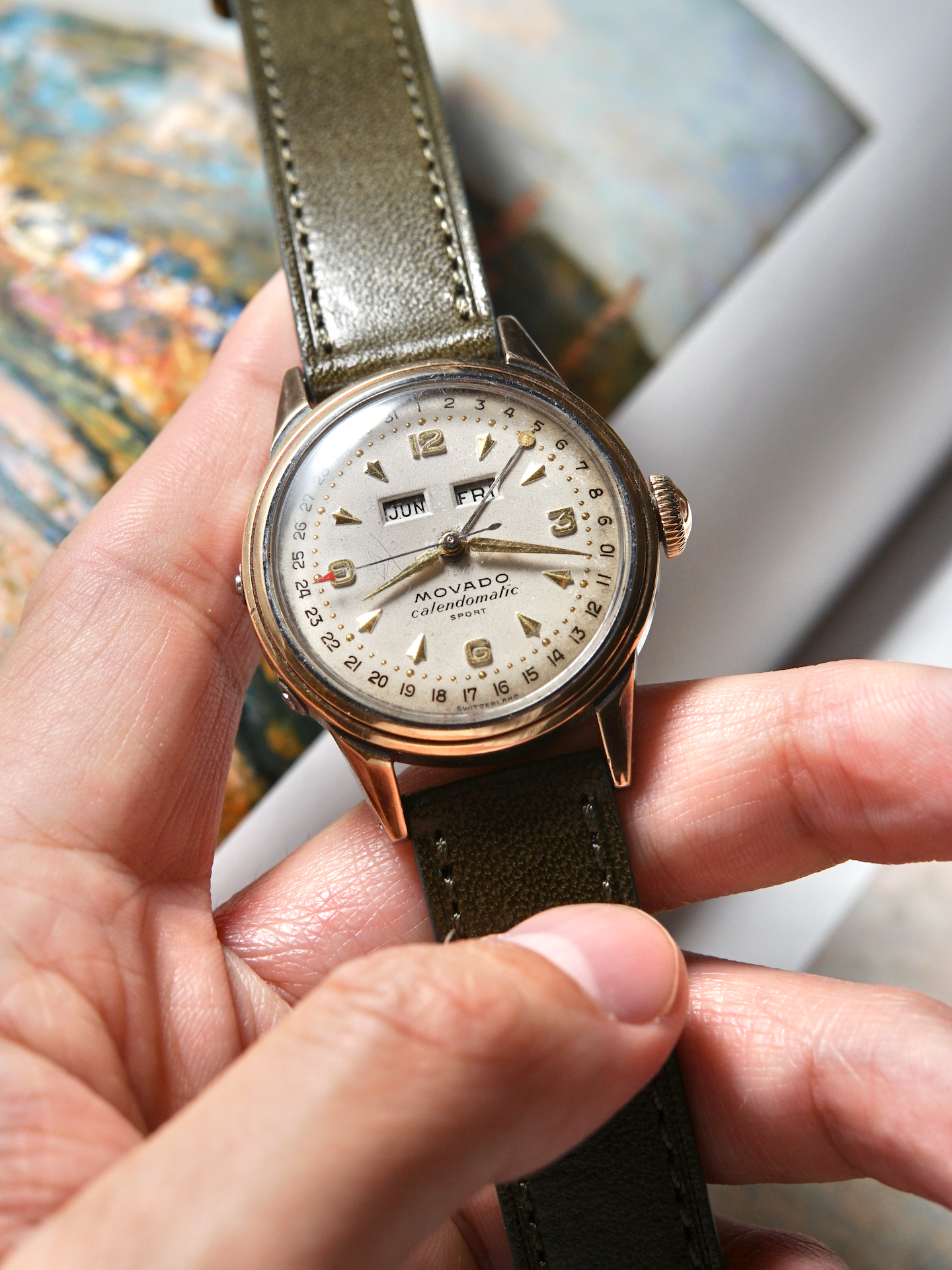 Vintage Movado watch held in a hand with a blurred background